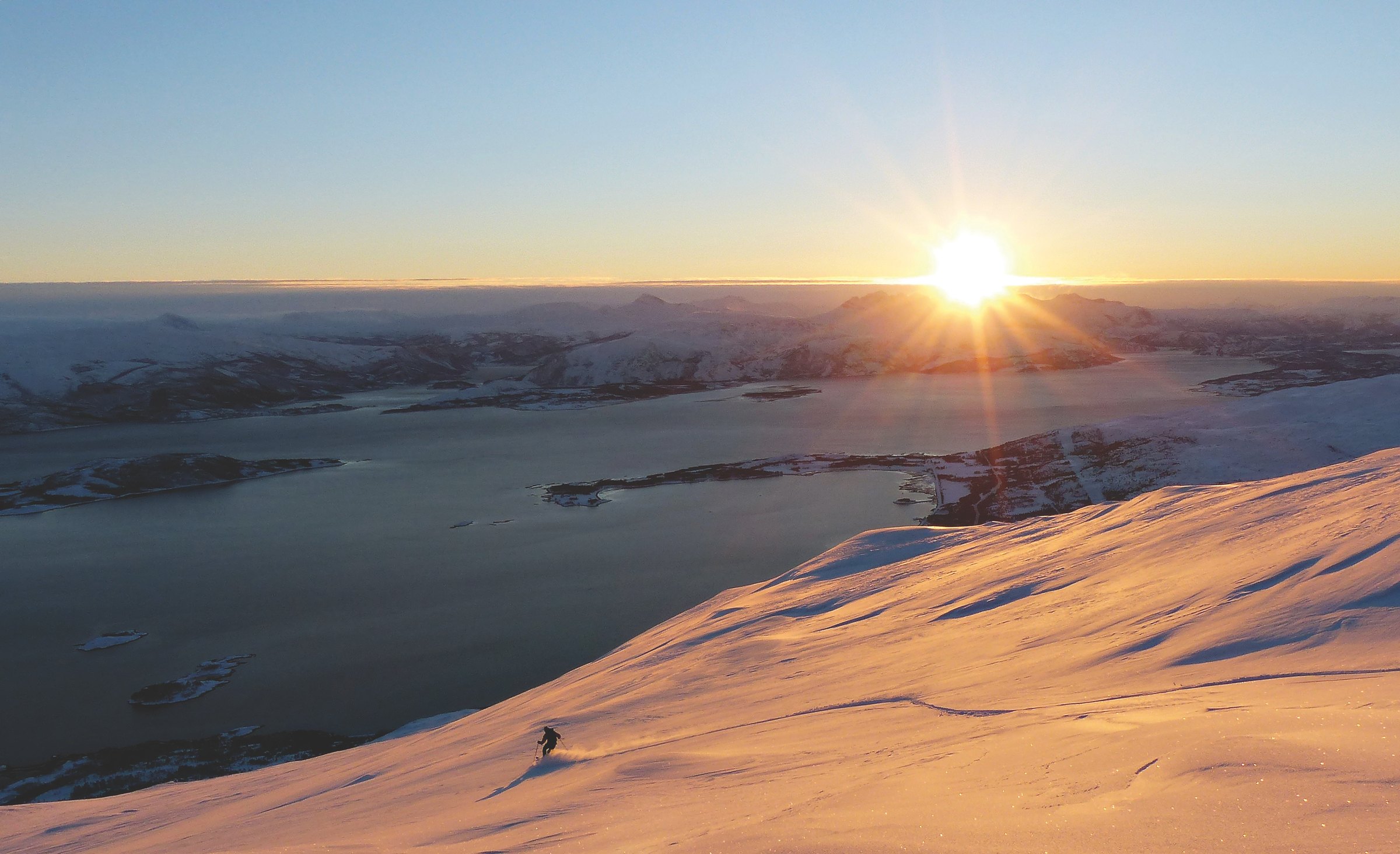 Skikjører i lav vintersol på Kistrandtindan i Valnesfjorden ved Bodø, med fjord og øyer i bakgrunnen