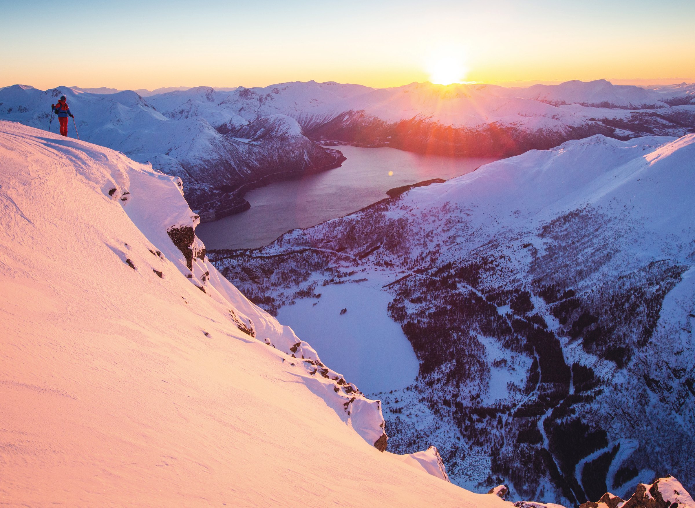 Skiløper i solnedgang på en fortopp til Snøhornet med utsikt over Aldalsvatnet og Austefjorden